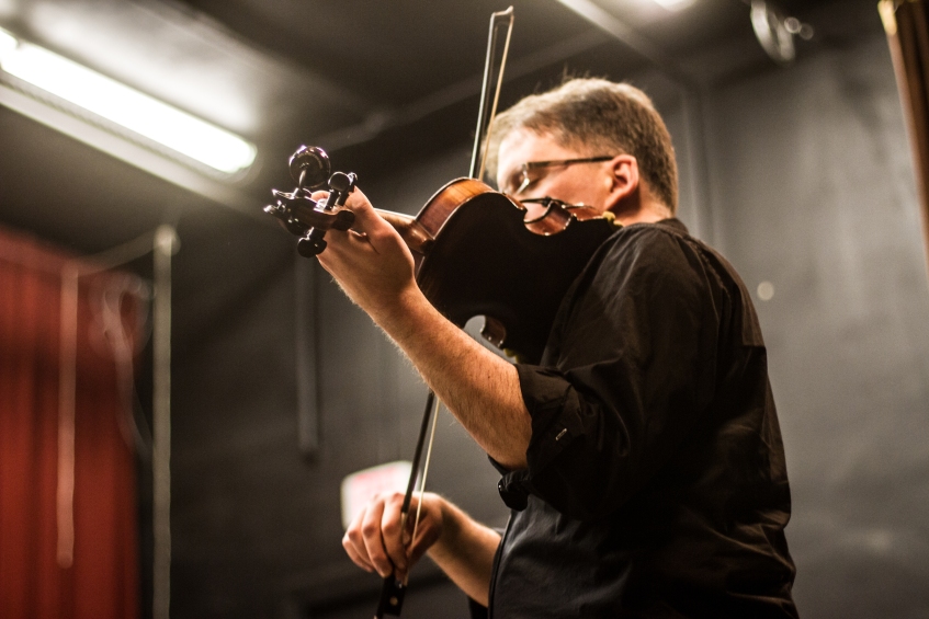A fiddler plays live music at a contra dance. Photo by Sam Whited, used here under Creative Commons license with thanks.